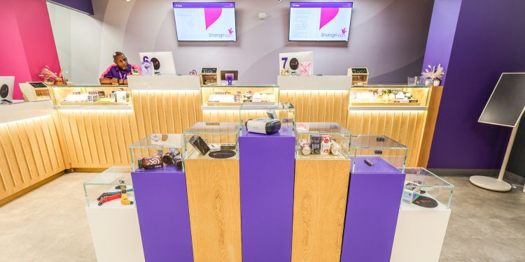 Bright, modern retail space with glass display cases showcasing various products and a staff member behind the counter